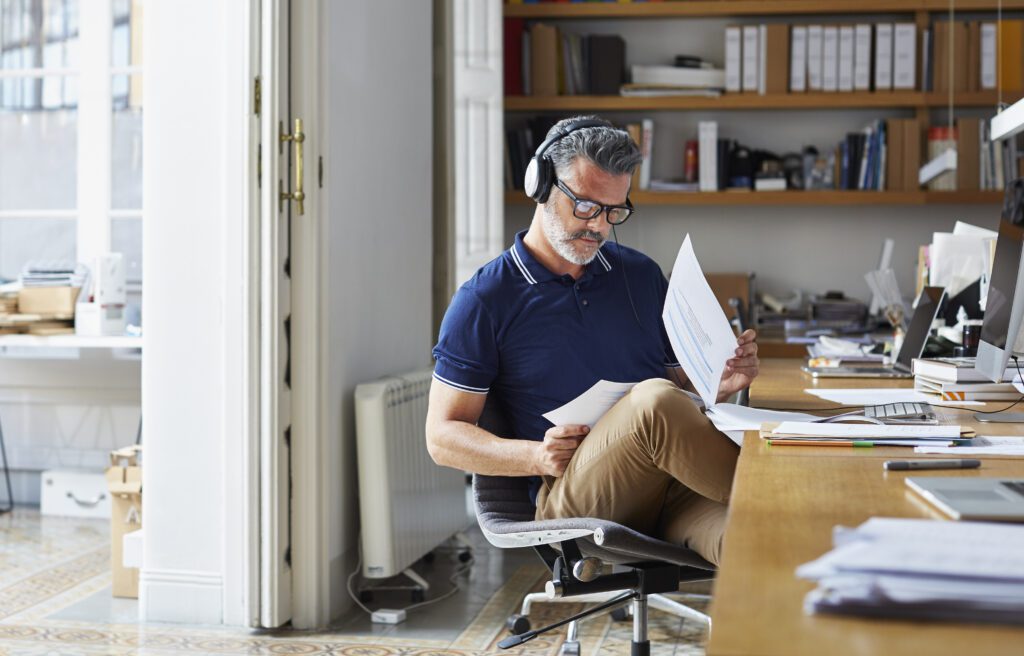 Mature businessman examining documents at desk in office.